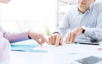 close up of wo people sitting at a desk reviewing a document