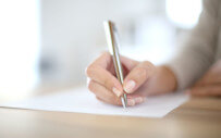 close up of a hand writing on a document