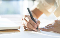 close up of hands writing on a document