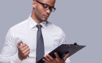 man looking at papers on a clipboard