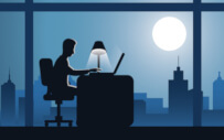 A silhouette of a man working at his office desk.