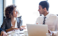 man and woman talking at a desk