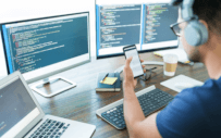 Person looking at phone and laptop