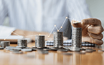 A line graph superimposed upon a growing stack of coins.